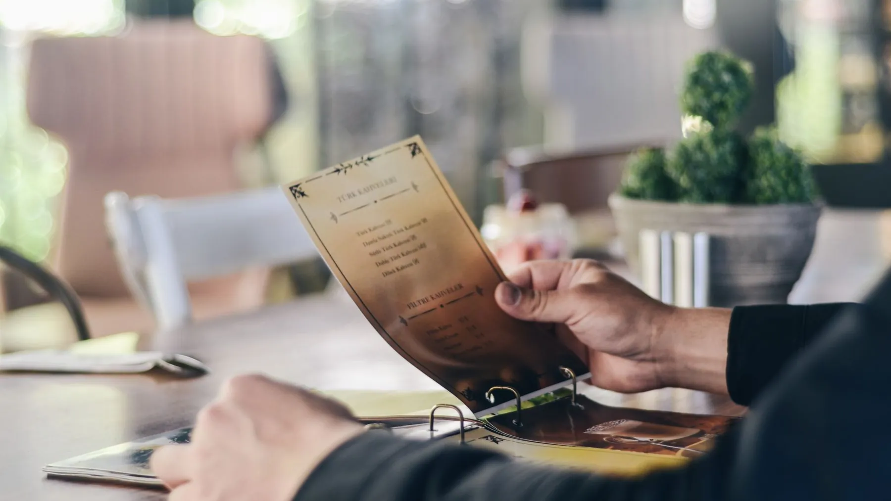 A guest holding a printed restaurant menu at a table